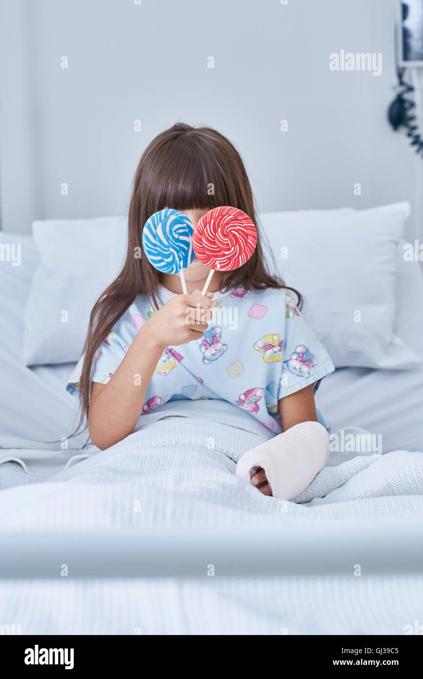 Portrait of Girl holding patient lollipops devant ses yeux à l'hôpital de pédiatrie Banque D'Images