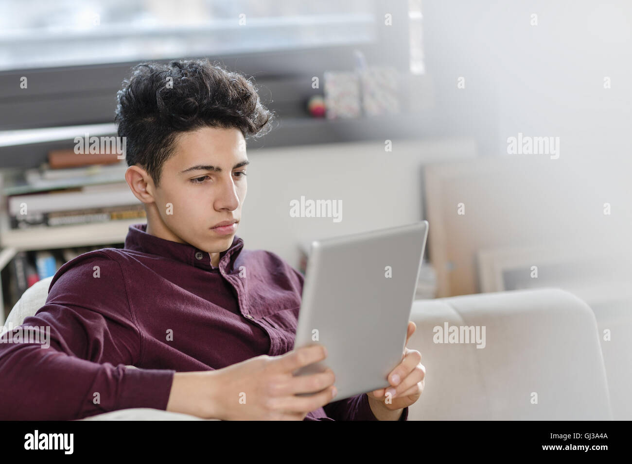 Jeune homme on sofa using digital tablet Banque D'Images