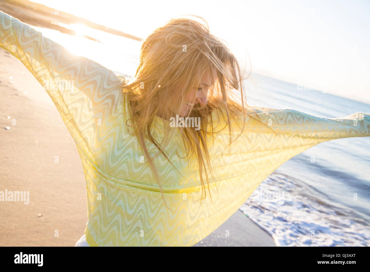 Young woman on beach, danse, smiling Banque D'Images