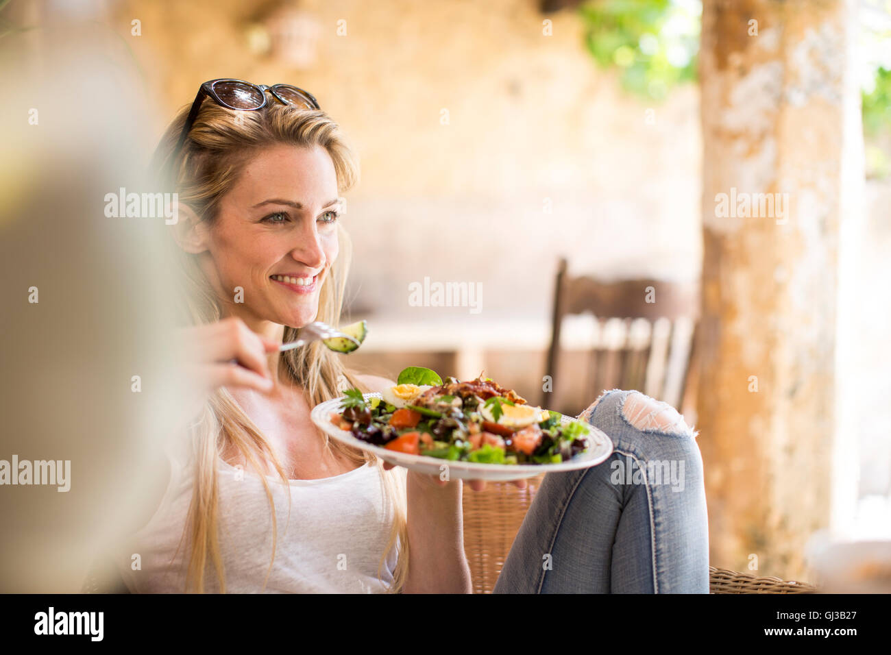 Young woman relaxing on patio jardin eating salad Banque D'Images