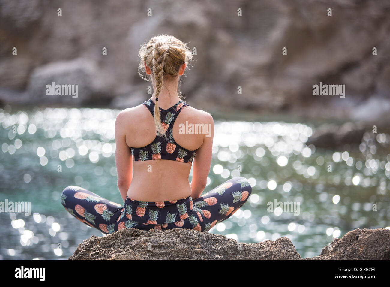 Young woman practicing yoga position du lotus sur les rochers marins, Majorque, Espagne Banque D'Images