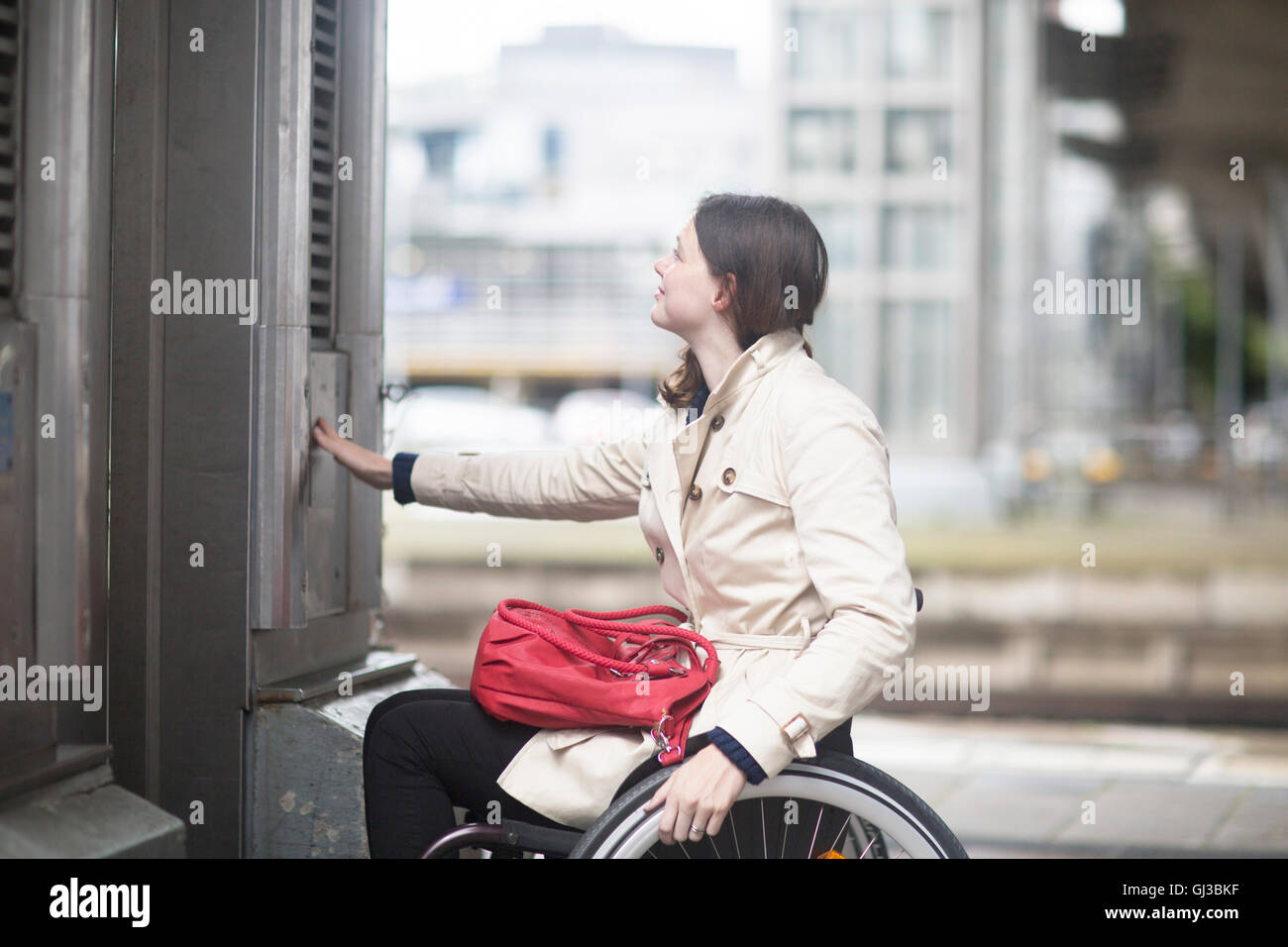 Jeune femme en utilisant la touche control pour fauteuil roulant ascenseur ville Banque D'Images