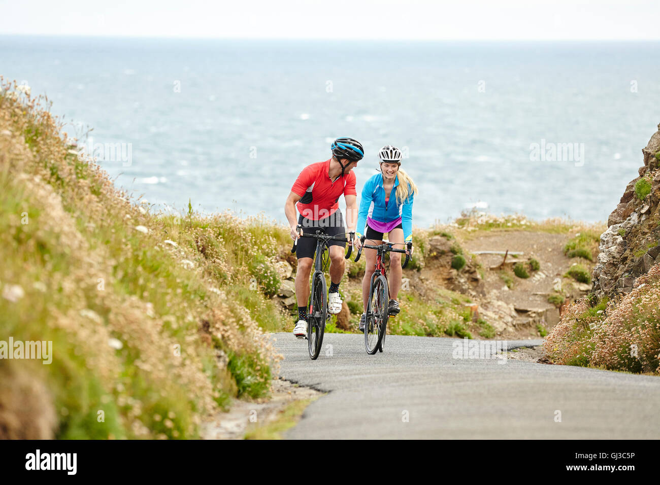 Cyclists riding on road overlooking ocean Banque D'Images