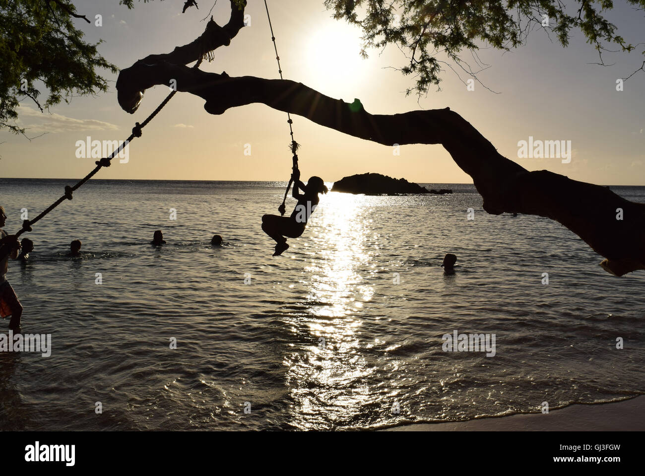 Kid sur l'oscillo silhouette sautant à la corde à l'océan, au crépuscule Banque D'Images