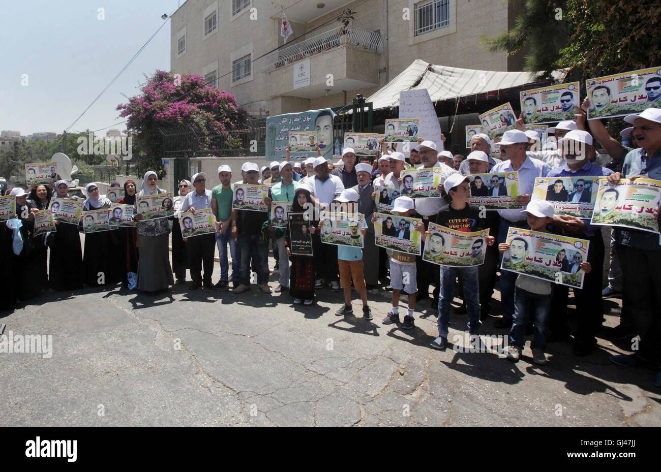 Jérusalem, Jérusalem, territoire palestinien. 12Th Aug 2016. Des manifestants palestiniens tenir affiches contre la détention administrative et à l'appui du prisonnier palestinien Bilal Kayed (portrait), qui avait jeûné pendant près de deux mois au cours de sa détention sans procès, comme ils démontrent à l'extérieur de la Croix-Rouge à Jérusalem est le 12 août 2016. Credit : ZUMA Press, Inc./Alamy Live News Banque D'Images