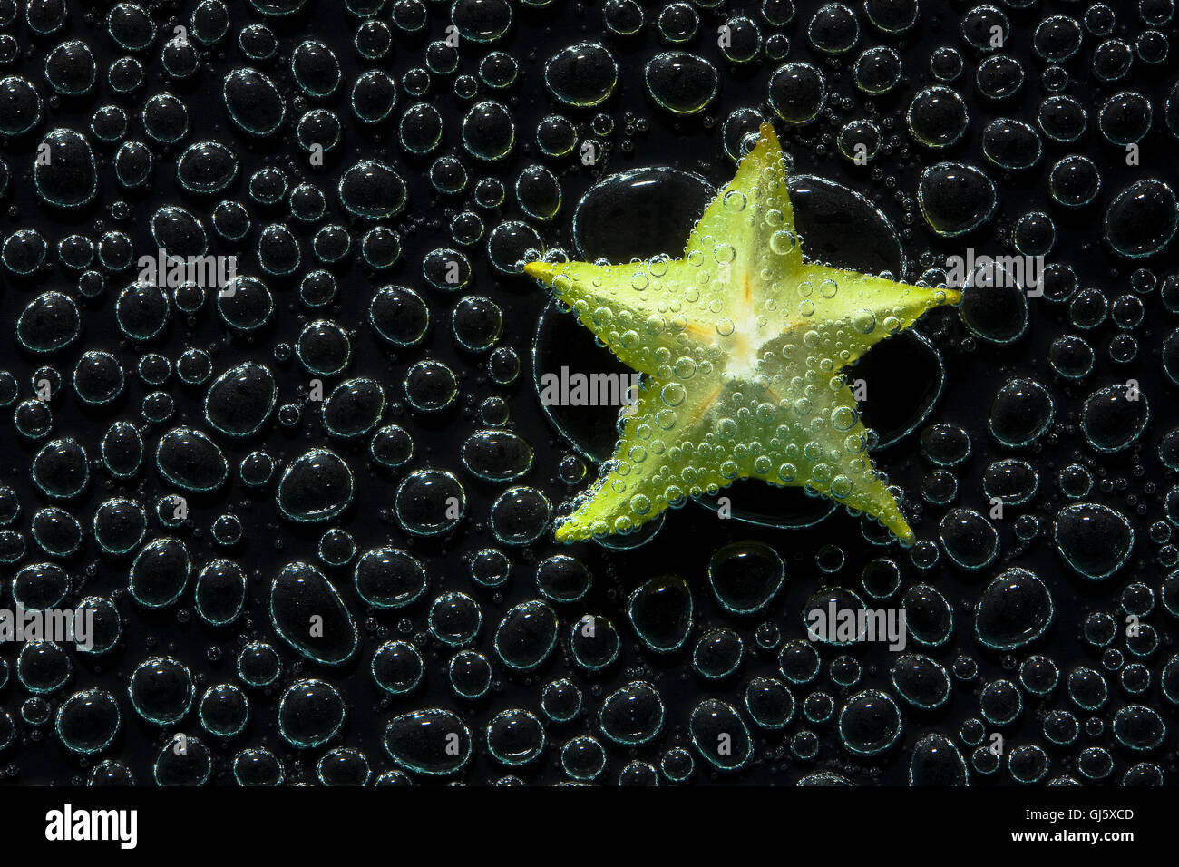 La carambole, star-fruits Fruits dans de l'eau minérale, une série de photos. Close-up de l'eau gazéifiée sur fond noir Banque D'Images