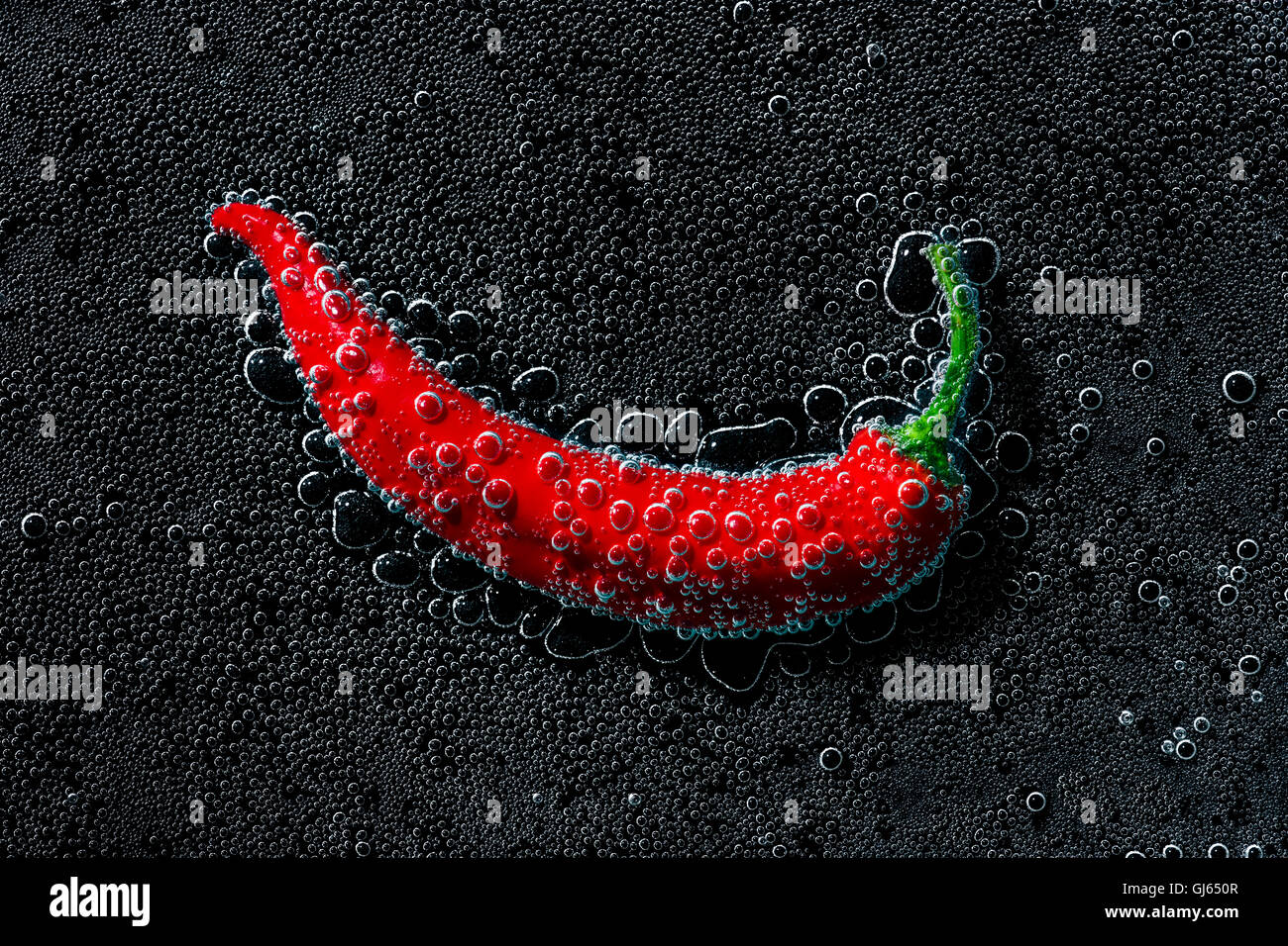 Chili Pepper dans une eau minérale, une série de photos. Close-up de l'eau gazéifiée sur fond noir Banque D'Images