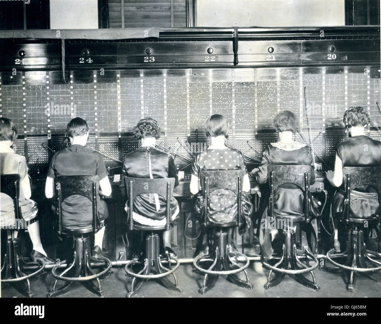 Vue sur une rangée de téléphonistes assis à un standard téléphonique. Banque D'Images