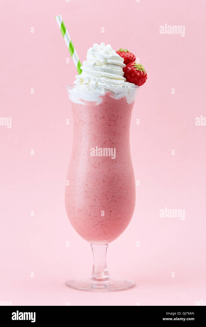 Verre de lait fouetté aux fraises avec de la crème fouettée et de fraises fraîches sur fond rose Banque D'Images