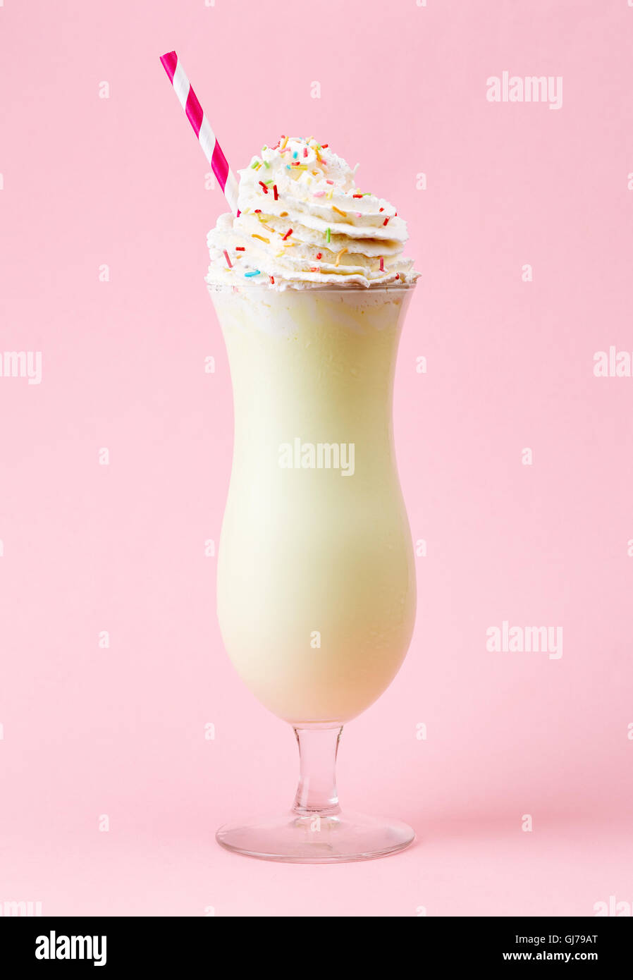 Verre de lait aromatisé à la vanille avec de la crème fouettée sur fond rose Banque D'Images