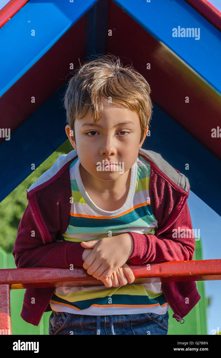 Un jeune garçon pose pour une photo au haut d'une diapositive d'une aire de jeux pour enfants. Banque D'Images