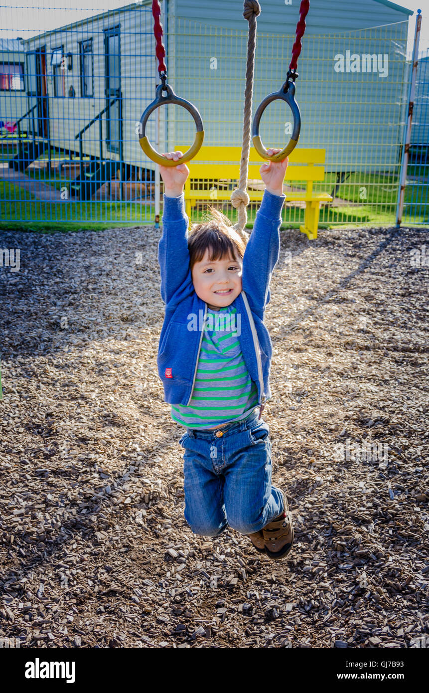 Un jeune garçon joue sur les bagues dans une aire de jeux pour enfants. Banque D'Images
