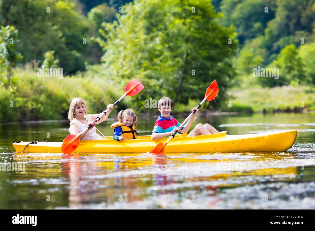 Famille heureuse avec deux enfants bénéficiant de belle rivière en kayak. Maman avec petite fille et garçon adolescent kayak Banque D'Images