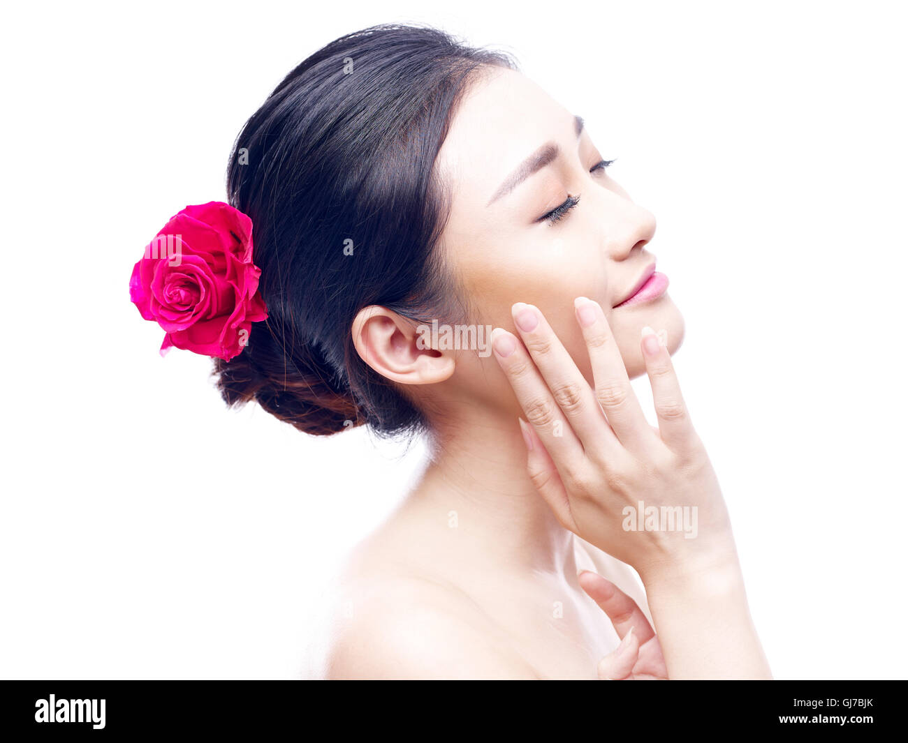 Portrait d'une jeune et belle asiatique femme avec rose rouge dans les cheveux, vue latérale, isolé sur fond blanc. Banque D'Images