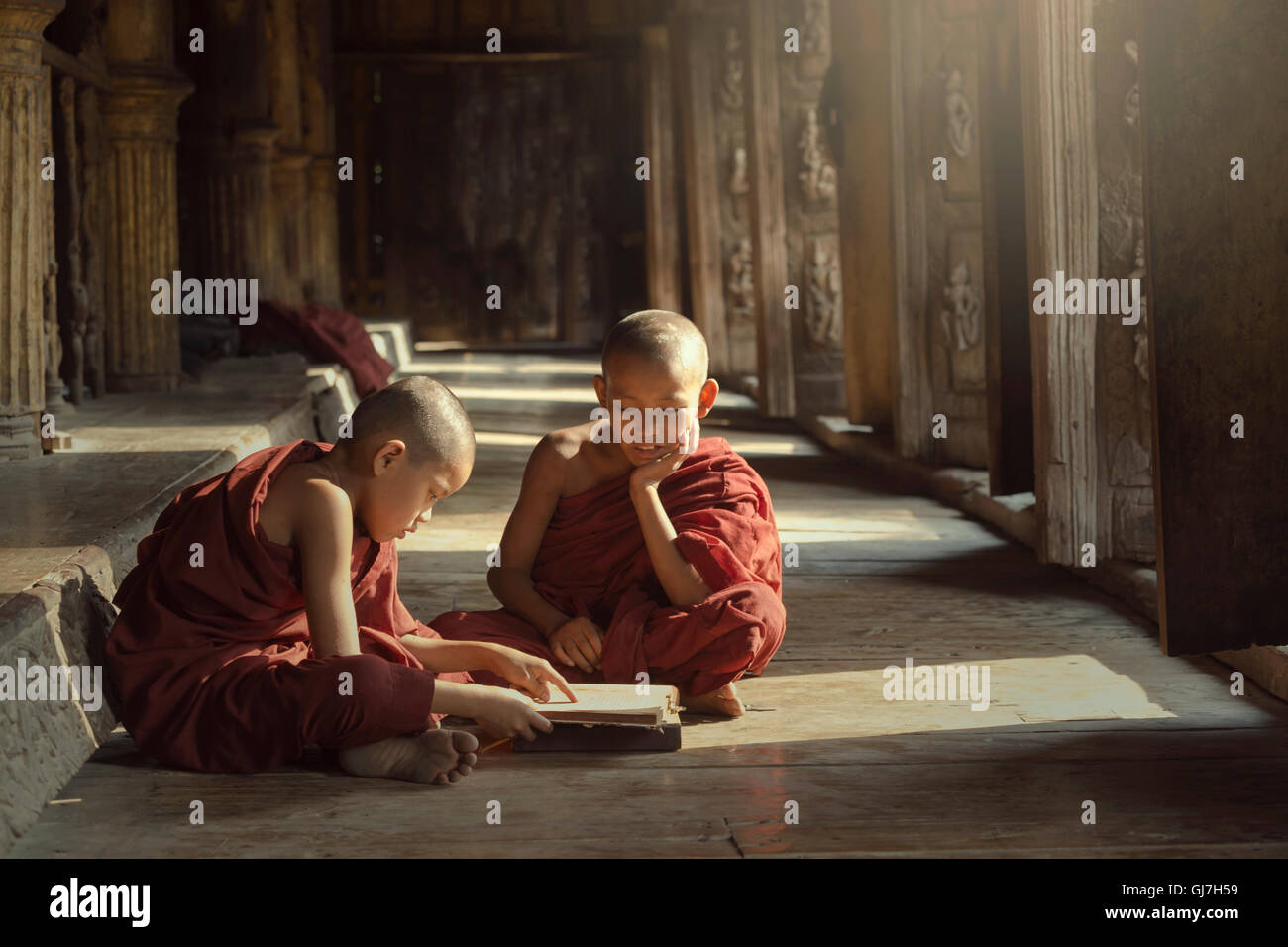 Deux novices sont la lecture d'un livre sur le Temple à Mandalay, Birmanie Banque D'Images