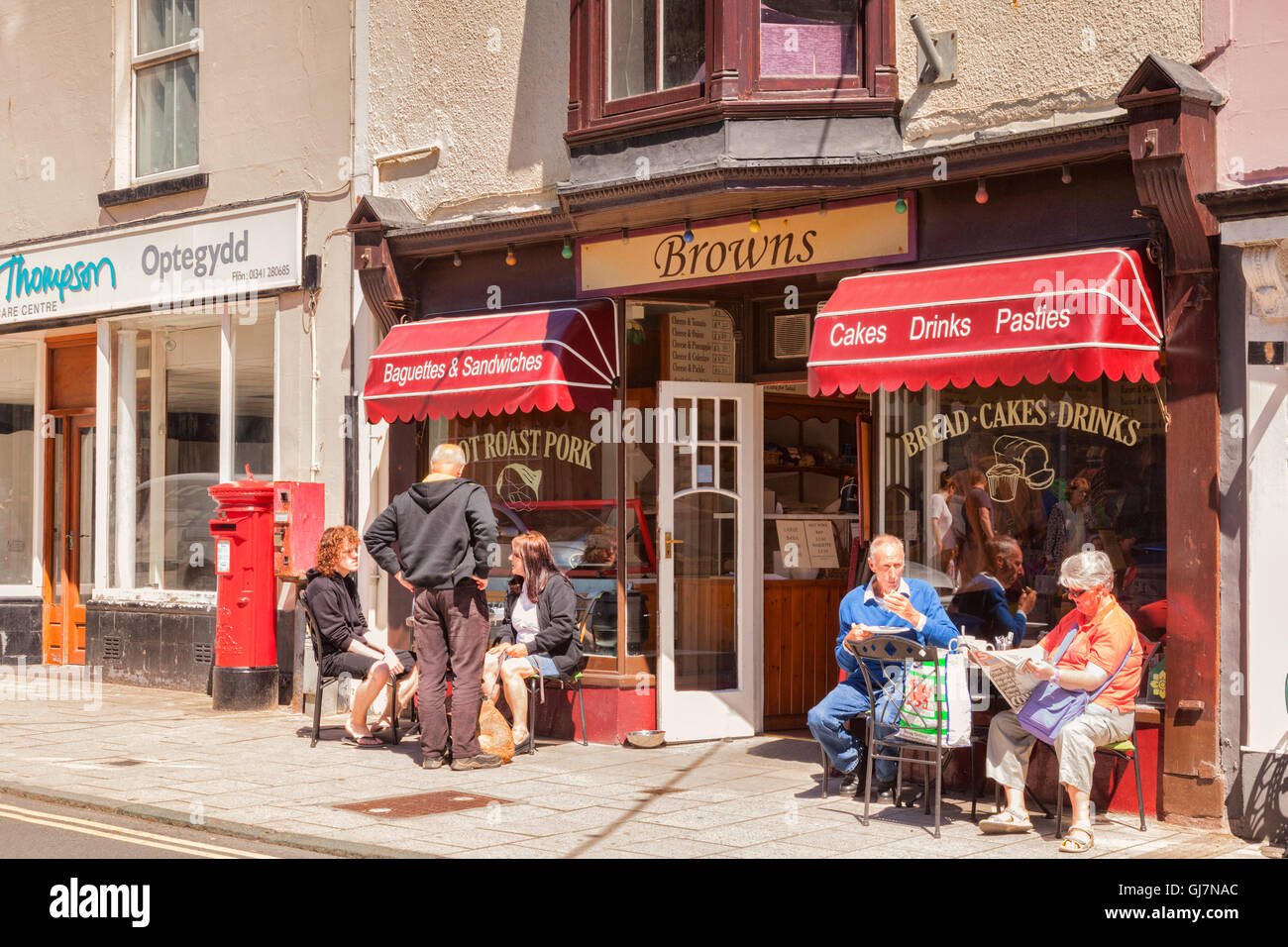 Les gens assis dans le soleil à l'extérieur marron dans la rue de l'Église, Barmouth, Gwynedd, Pays de Galles, Royaume-Uni Banque D'Images