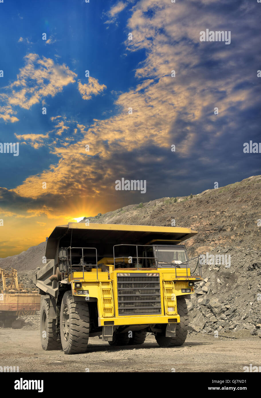 Camion benne poids lourds transportant du minerai de fer à ciel ouvert sur le coucher du soleil Banque D'Images