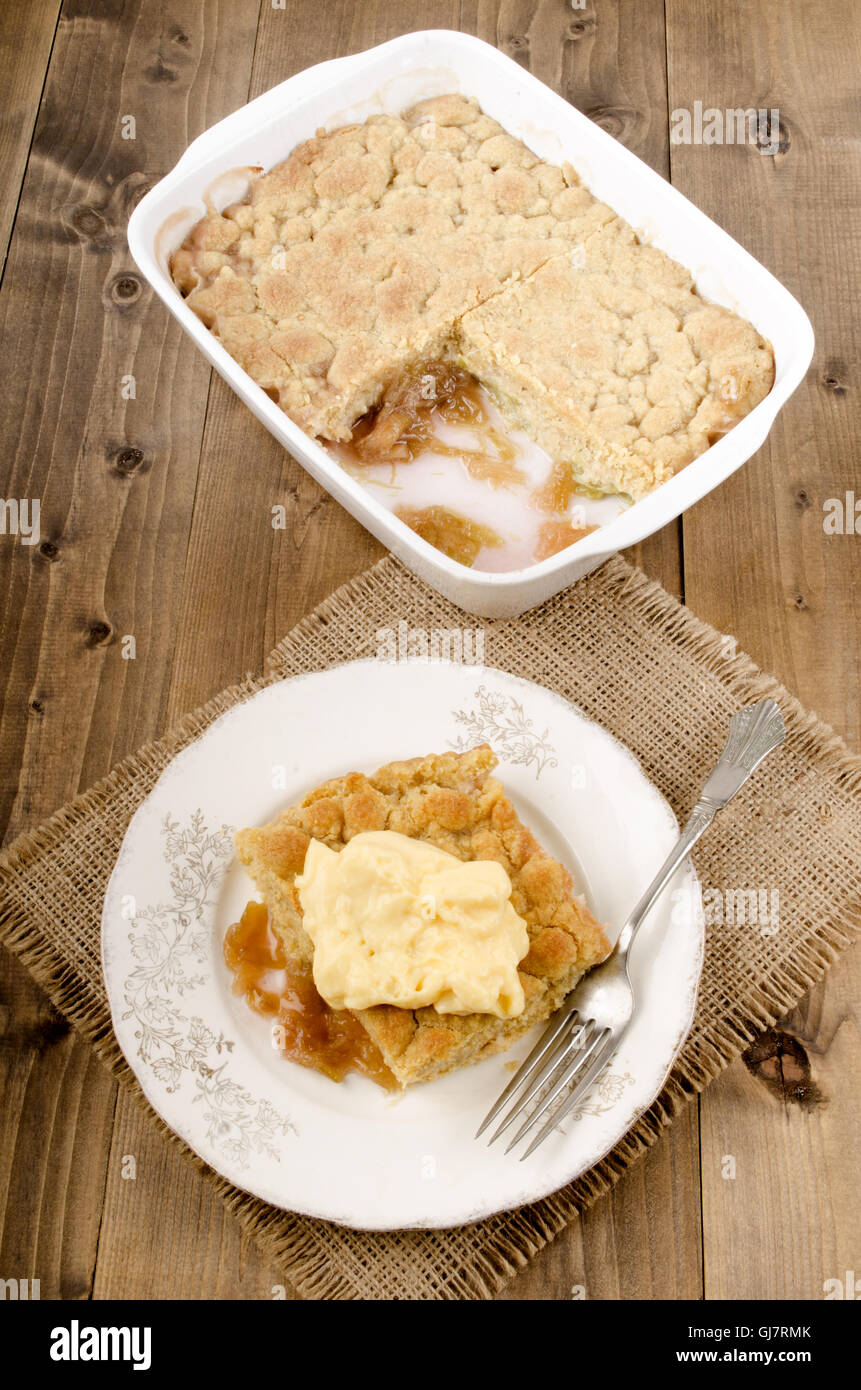 Crumble rhubarbe fraîchement cuits au four avec de la crème anglaise sur une assiette Banque D'Images