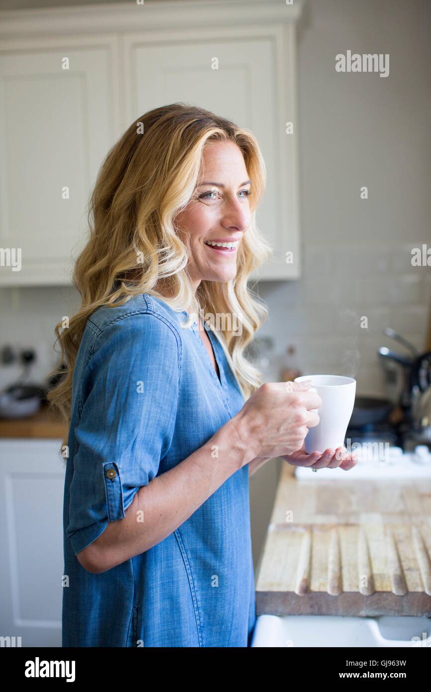Parution de la propriété. Parution du modèle. Femme en cuisine avec boisson chaude, portrait. Banque D'Images
