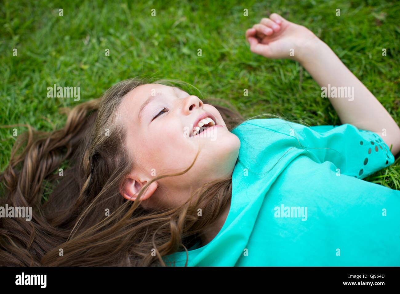 Parution de la propriété. Parution du modèle. Jeune fille couchée sur l'herbe, souriant. Banque D'Images