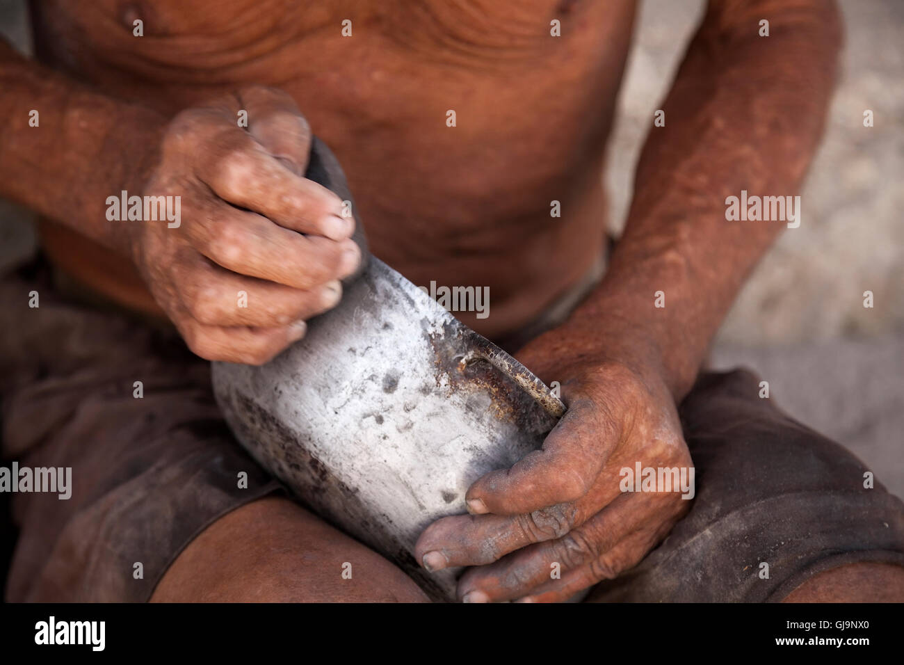 Un homme nettoyer un pot coloré à l'aide d'un rocher dans la municipalité de Regla, La Havane, Cuba. Banque D'Images