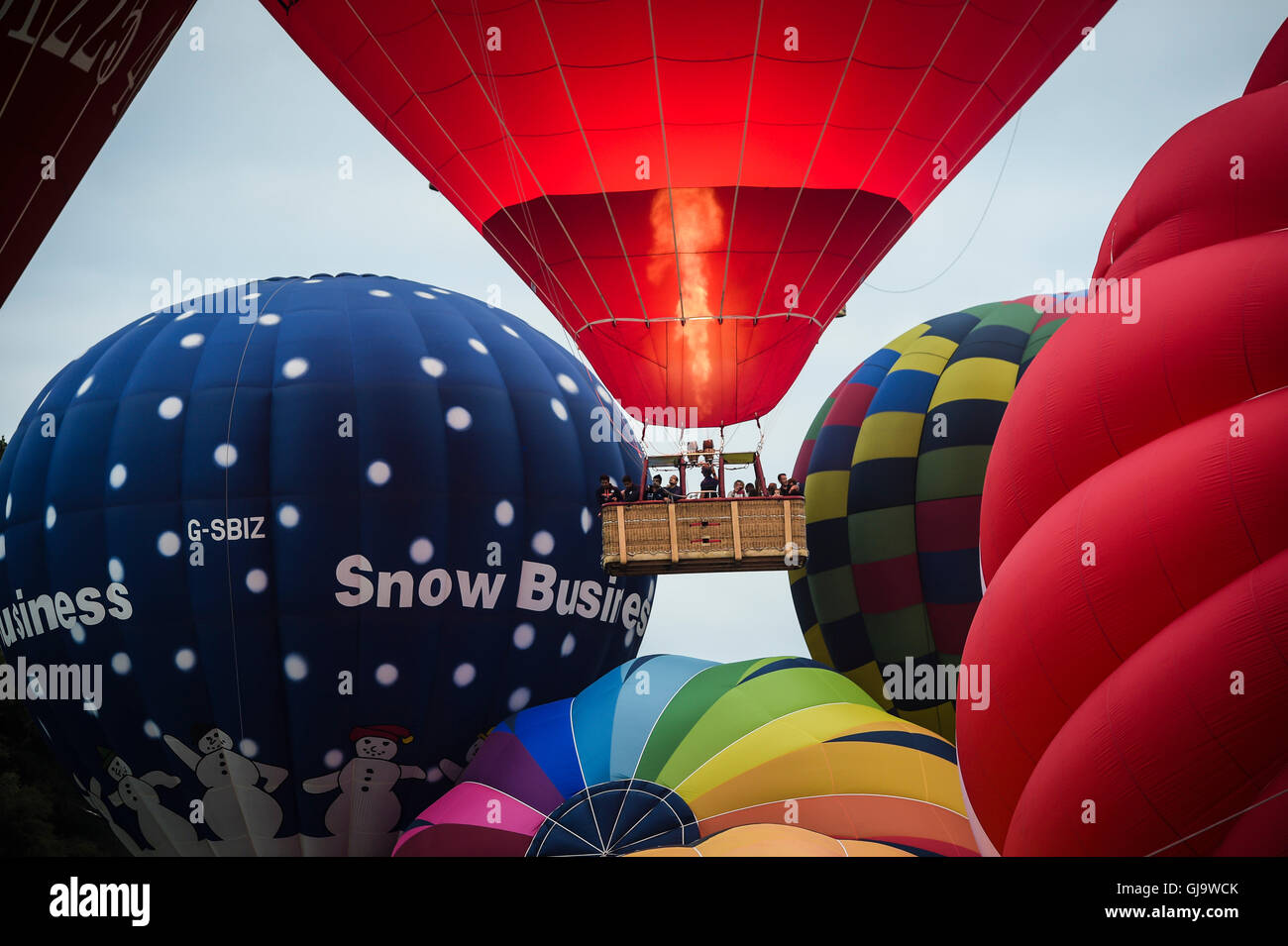 Avec les brûleurs à fond une montgolfières décoller dans une ascension de masse au Bristol International Balloon Fiesta, Ashton Court Estate. Banque D'Images