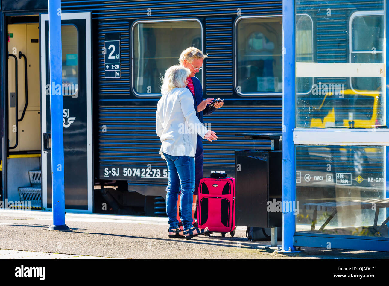 Kalmar, Suède - le 10 août 2016 : un couple debout sur le quai de la gare en face d'un wagon de train. Ils exploitent un Banque D'Images Kalmar, Suède - le 10 août 2016 : un couple debout sur le quai de la gare en face d'un wagon de train. Ils exploitent un Banque D'Images