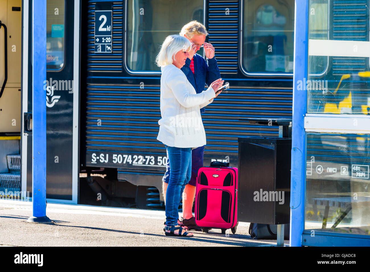 Kalmar, Suède - le 10 août 2016 : un couple debout sur le quai de la gare en face d'un wagon de train. Ils exploitent un Banque D'Images Kalmar, Suède - le 10 août 2016 : un couple debout sur le quai de la gare en face d'un wagon de train. Ils exploitent un Banque D'Images