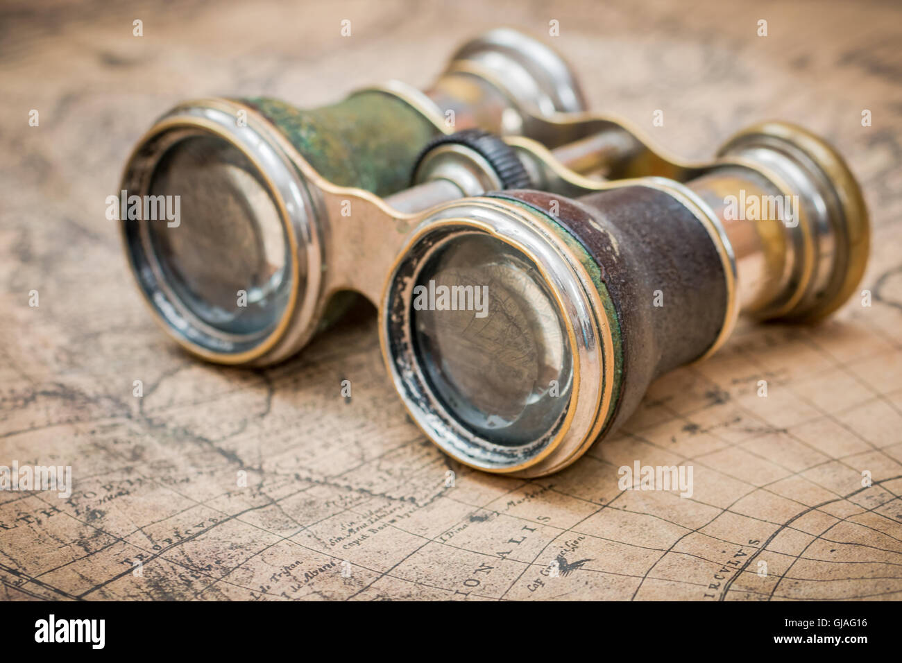 Explorer le monde photo concept avec une paire de jumelles sur une carte antique Banque D'Images