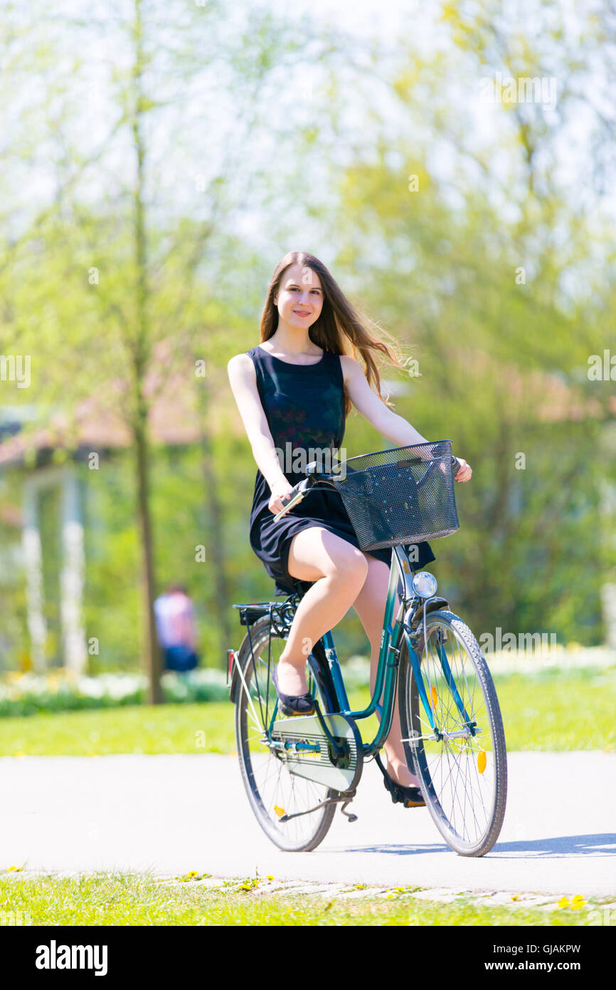 Jeune femme portant robe courte noire riding bike Banque D'Images