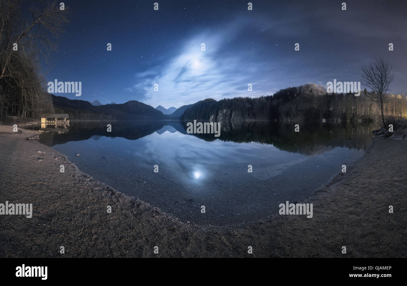 Nuit dans le lac Alpsee en Allemagne. Beau paysage avec le lac, les montagnes, la forêt, les étoiles, la pleine lune Banque D'Images