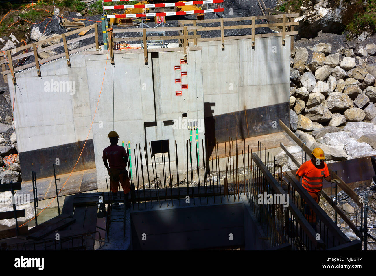 Les travailleurs qui construisent le mur de béton l'endiguement de la rivière Spiggen pour réservoir hydroélectrique, Alpes Bernoises, Suisse Banque D'Images