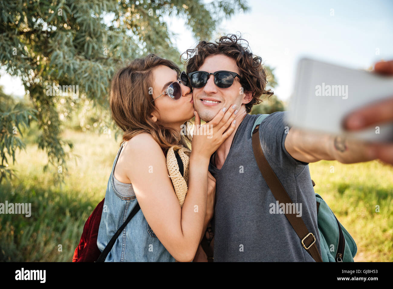 Young smiling couple heureux avec sacs à dos randonnée dans la forêt et faire selfies Banque D'Images