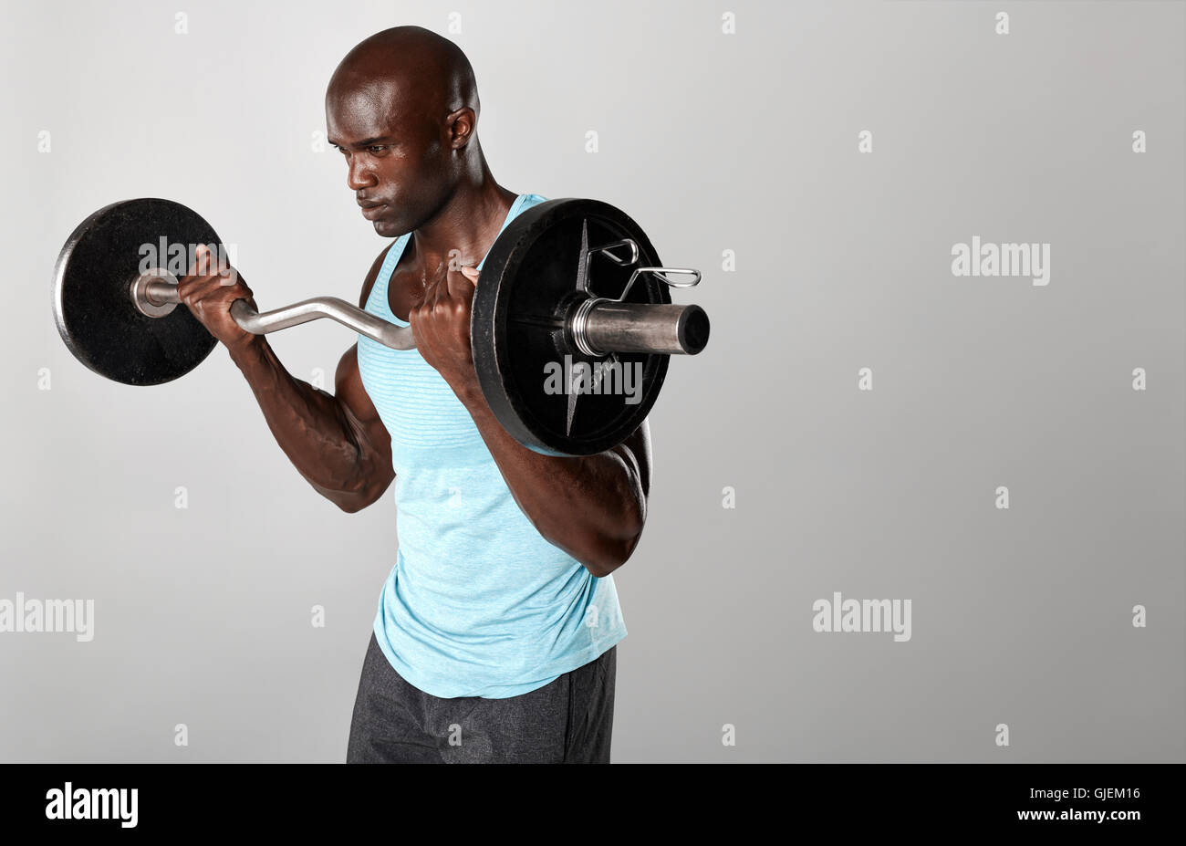 Portrait of young man lifting barbell fit contre fond gris. Jeune homme musclé s'entraîner avec des poids. Banque D'Images