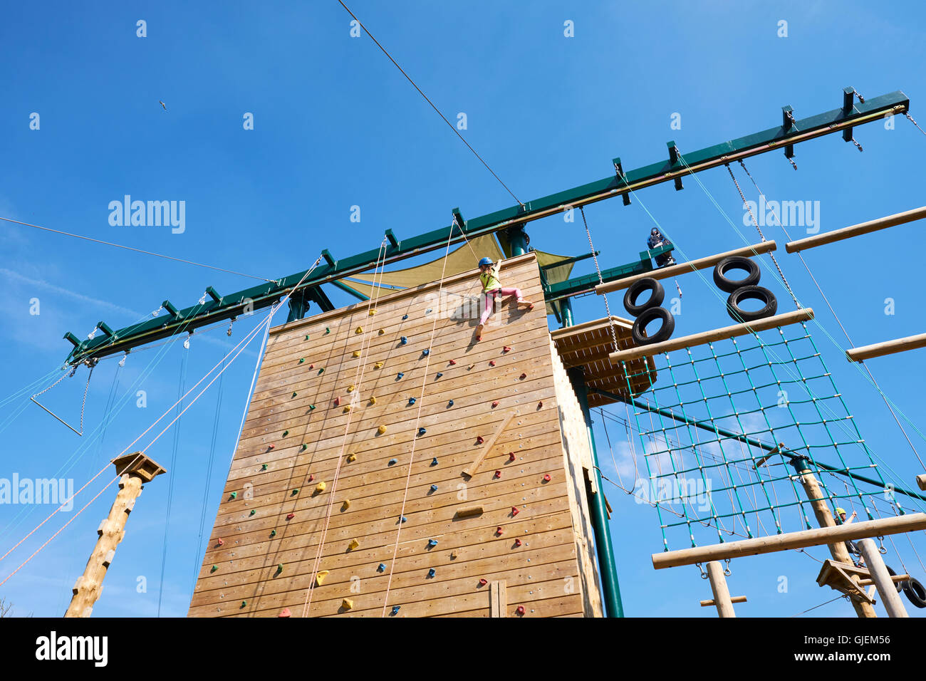 Jeune fille Atteindre le haut d'un mur d'escalade extérieur à Conkers une attraction à l'intérieur de la Forêt Nationale Moira Derbyshire UK Banque D'Images