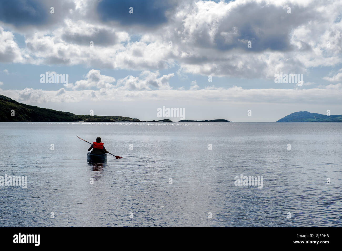 Une femelle de pagaies de kayak à l'écart de la rive de la mer sur une mer calme dans la région de West Cork, Irlande. Banque D'Images