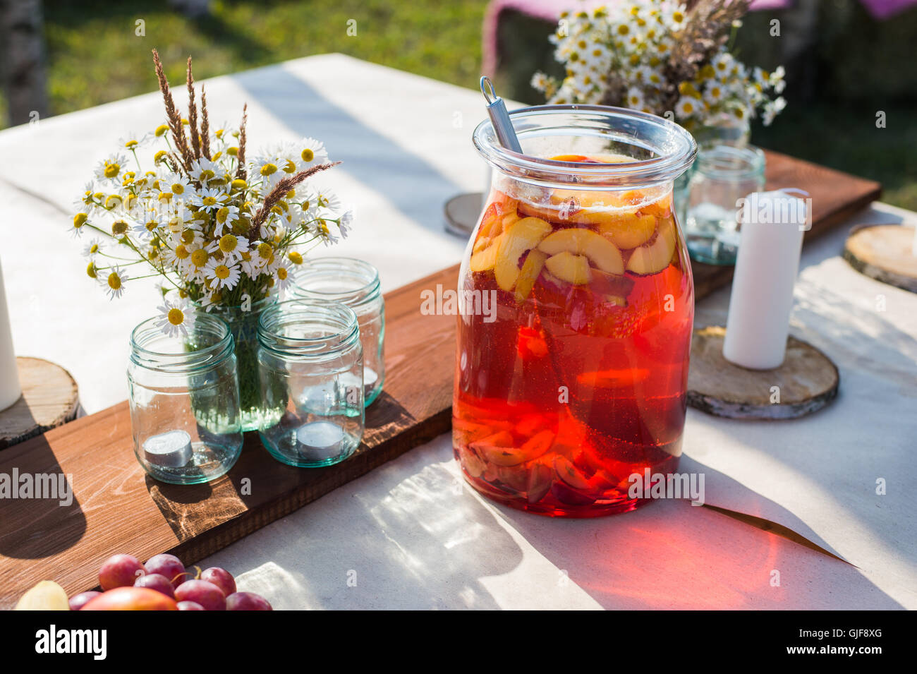 Compote de fruits frais, fleurs, bougies et sur table en bois libre. Focus sélectif. Belle décoration intérieure de style Boho. Banque D'Images
