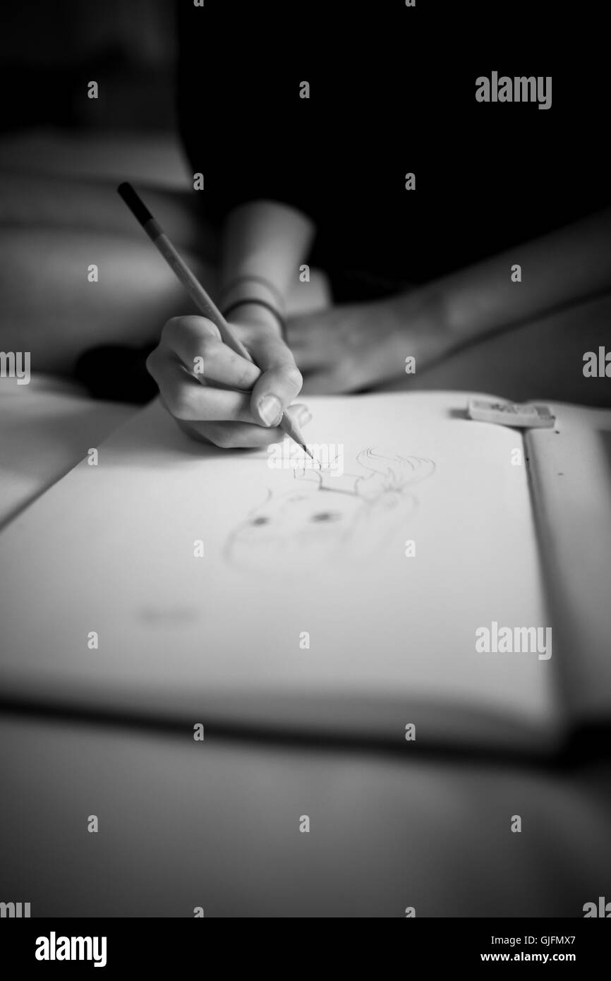 Les filles d'une main tenant un crayon et dessiner un visage, le style manga sur papier blanc. Banque D'Images