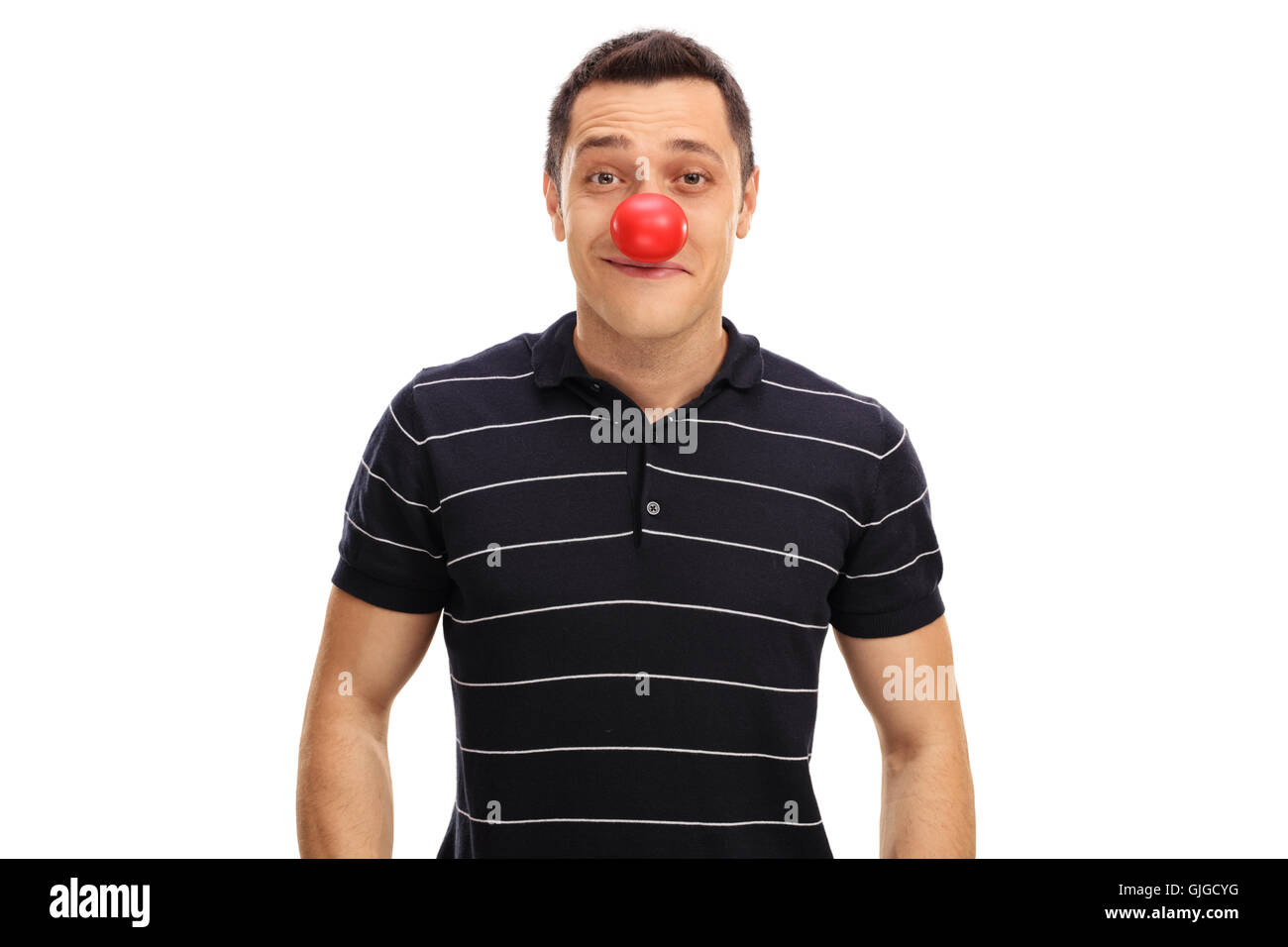 Jeune homme posant avec un nez de clown rouge isolé sur fond blanc Banque D'Images