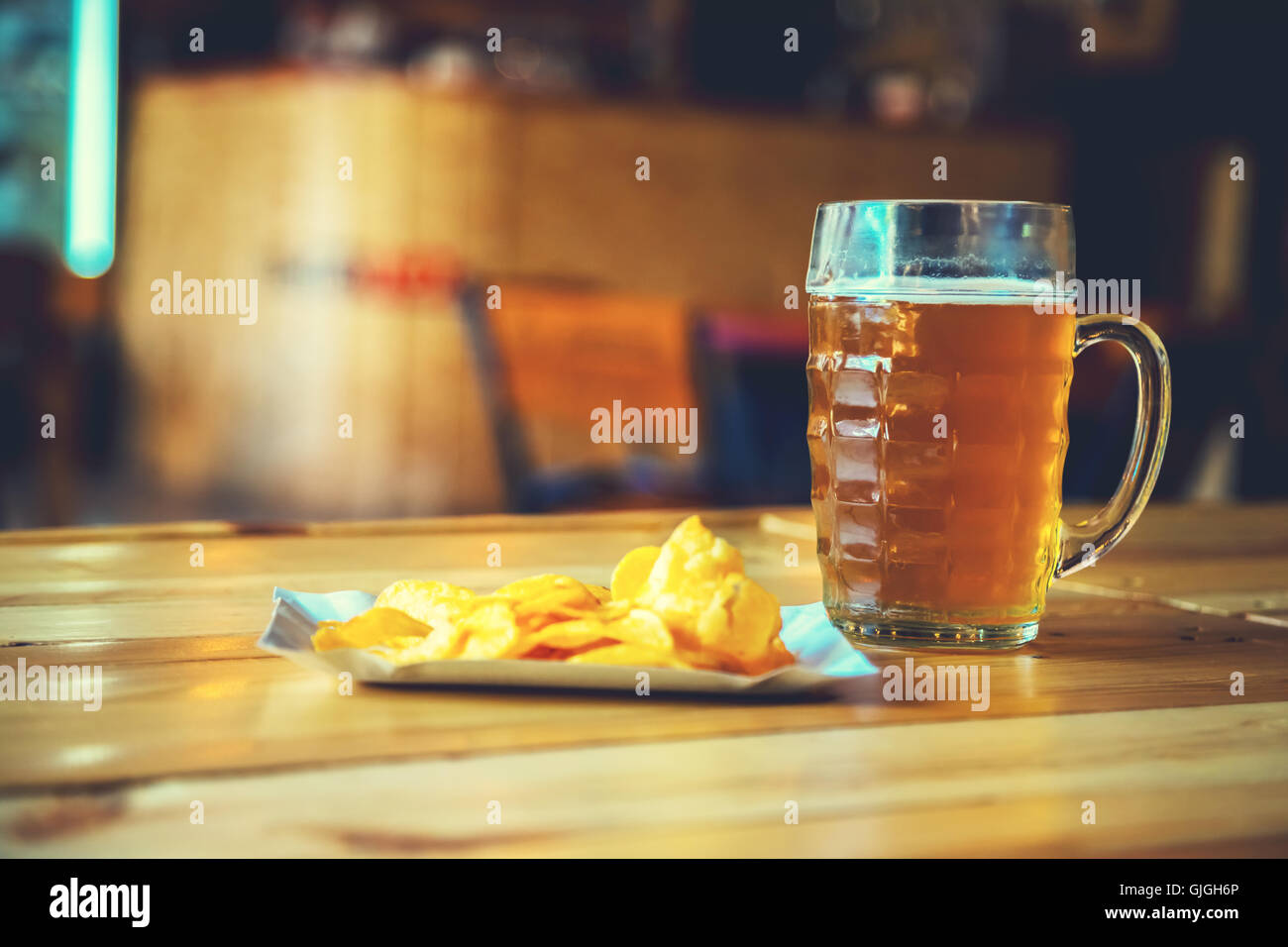 Un nouveau verre de bière de lumière froide et les chips de pomme de terre sur le comptoir du bar en bois dans un pub avec de l'espace libre pour votre texte. beau retour Banque D'Images