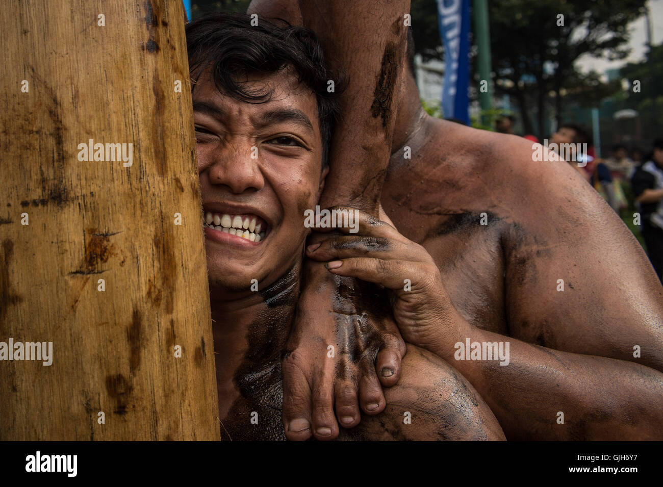 Jakarta, Indonésie. Août 17, 2016. Un homme réagit alors que son membre de l'équipe suit sur son épaule lors de l'escalade de poteaux pour célébrer le 71e jour de l'indépendance de l'Indonésie à Jakarta, Indonésie, le 17 août 2016. Chaque année, des gens autour de la ville de Jakarta grimper des centaines de poteaux, essayant d'obtenir des prix sur le sommet des poteaux pour célébrer le Jour de l'indépendance indonésienne. Sanovri Crédit : Veri/Xinhua/Alamy Live News Banque D'Images