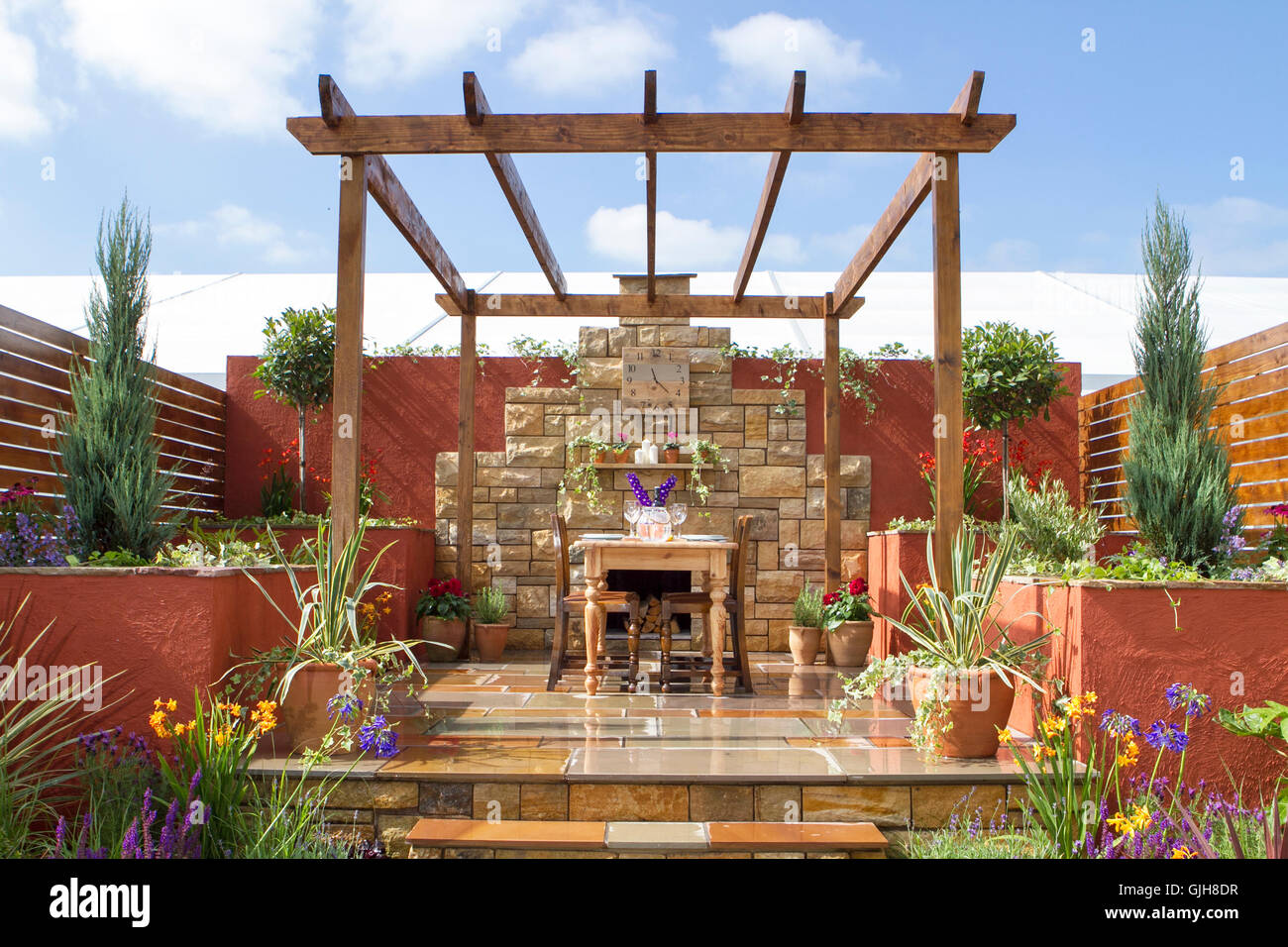 Jardin et patio de style espagnol avec table et chaises en bois au Southport Flower Show, Merseyside, Royaume-Uni. Bella Vista les derniers préparatifs sont en cours pour l'ouverture des jardins du salon des fleurs de Southport cette année, à laquelle des milliers de visiteurs sont attendus. Banque D'Images