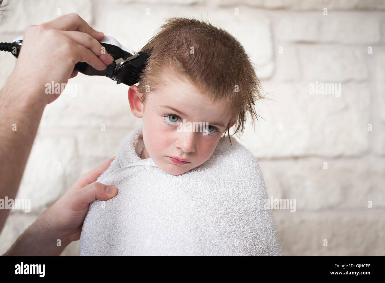 Boy Getting un buzz couper les cheveux par son père Banque D'Images