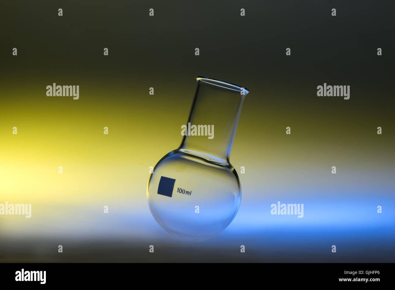 Fiole chimique à fond rond jaune en lumière bleue Banque D'Images