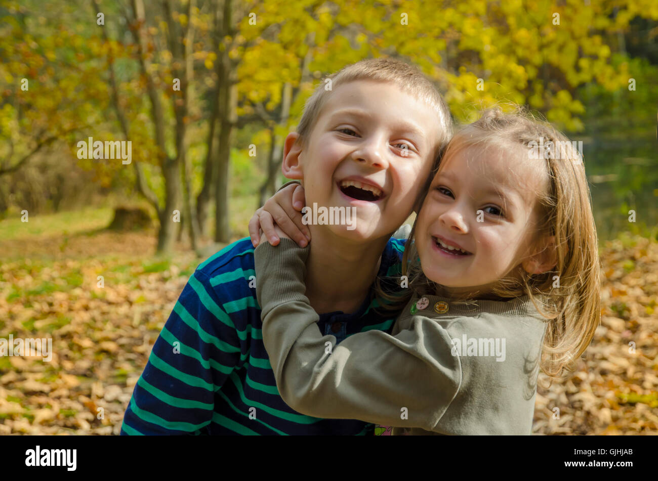 Garçon et fille souriant debout dans la forêt embrassant Banque D'Images