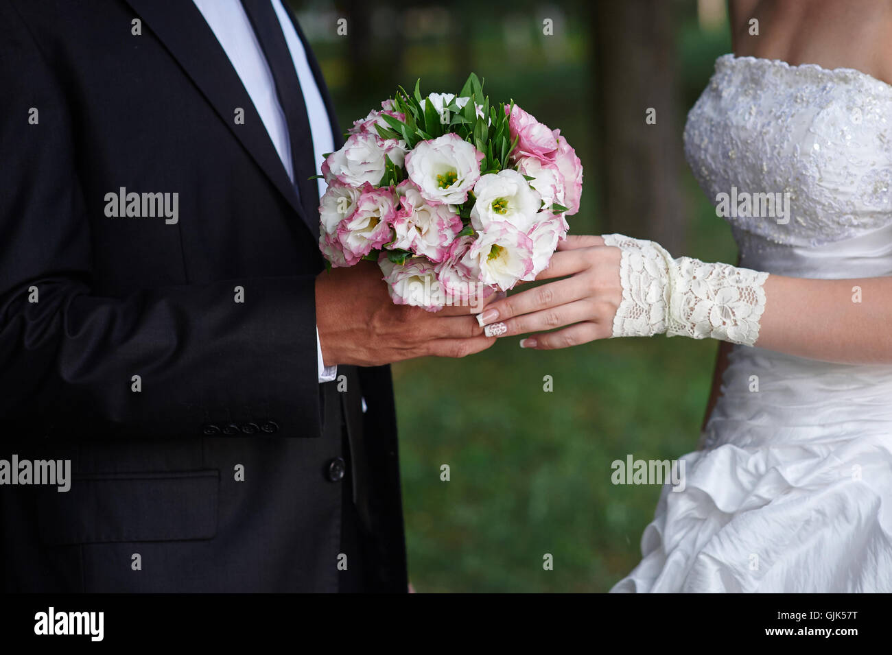 Le marié embrasse mariée, et elle détient un bouquet dans ses mains Banque D'Images