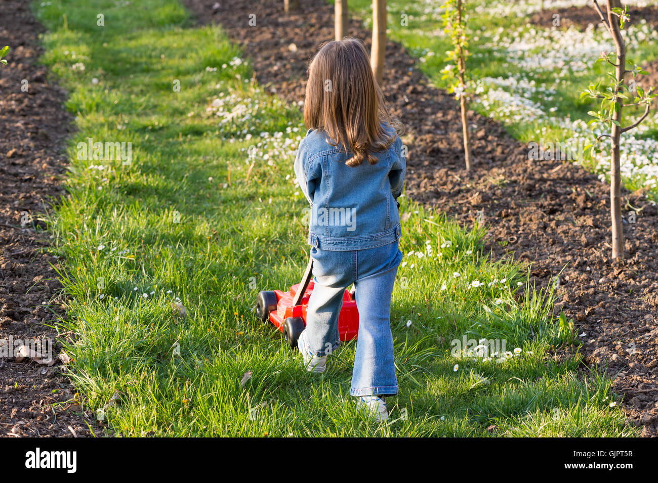 Jolie fille jouant avec une tondeuse dans le jardin Banque D'Images