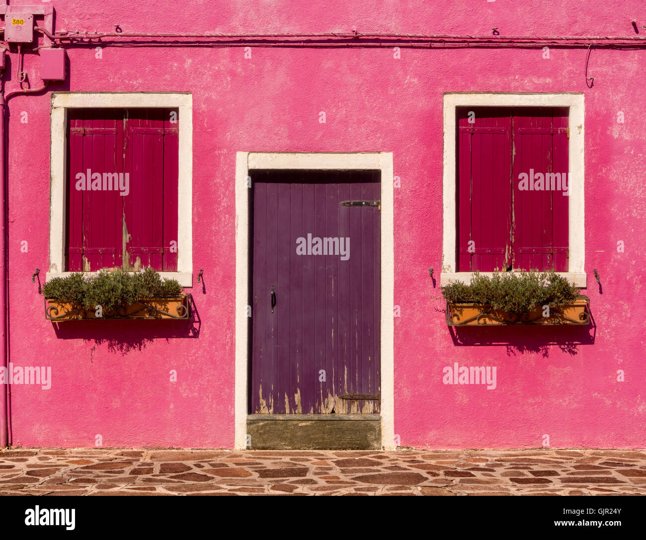Extérieur rose rendu d'une maison traditionnelle, avec porte pourpre sur l'île de Burano. Venise, Italie. Banque D'Images