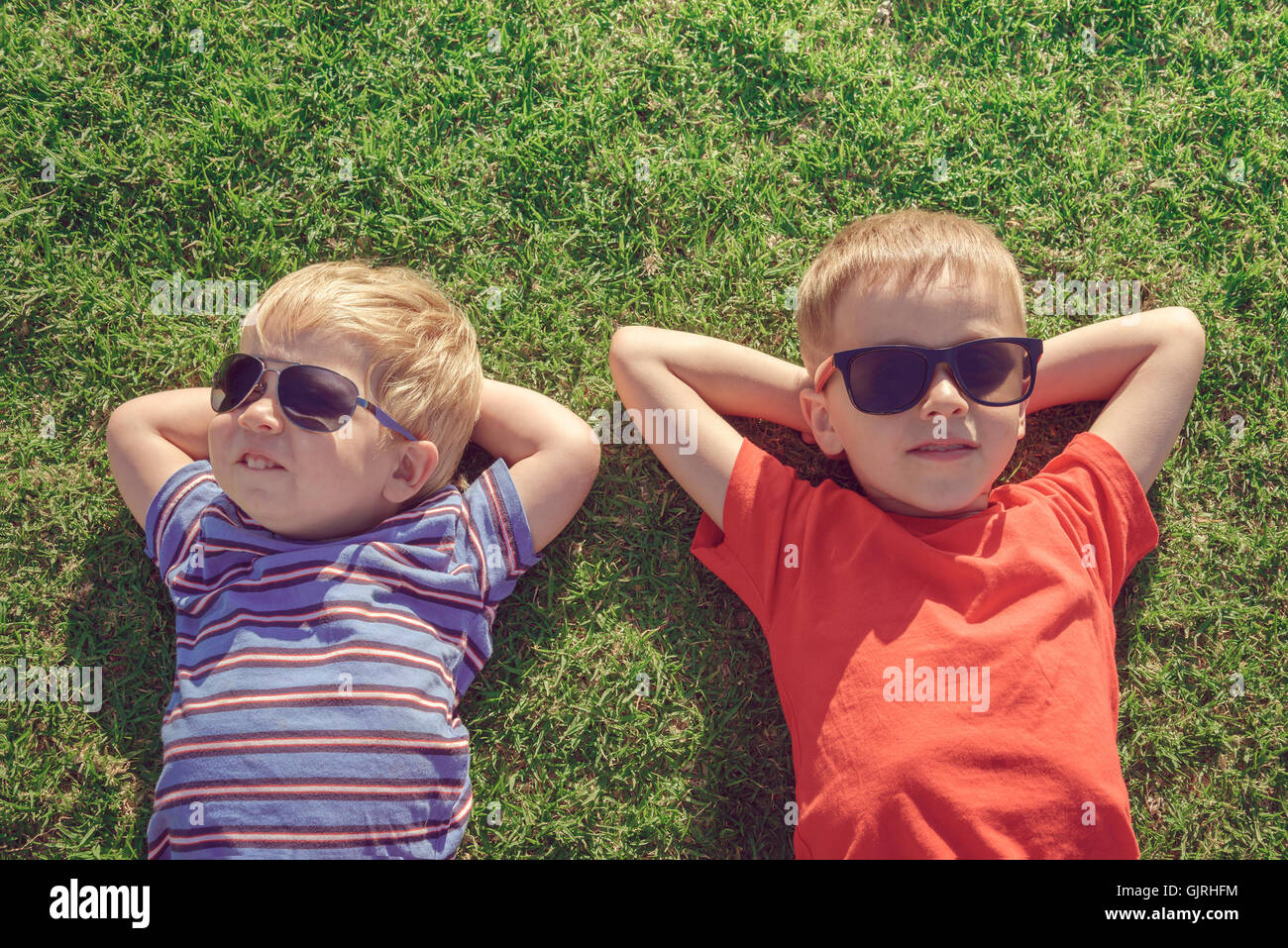 Happy smiling kids détente sur l'herbe, vue d'en haut. La tonalité de couleur appliqué Banque D'Images
