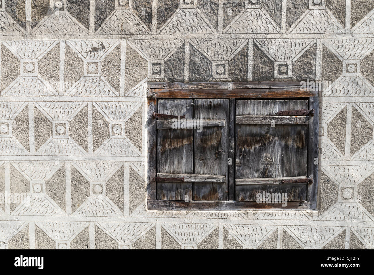 Un mur d'une maison rurale avec des ornements complexes et une petite fenêtre avec des volets en bois. La partie orientale de la Suisse. Banque D'Images
